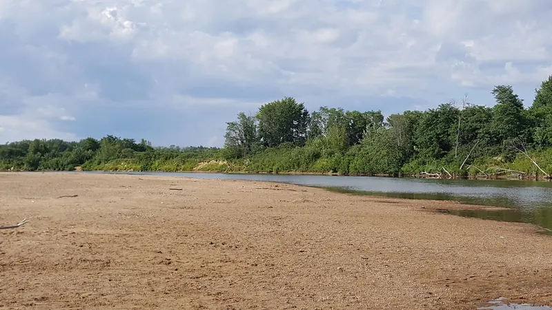 Historical sandy shoreline at Weston's Beach beside a bend in the Saco River and wooded opposite bank