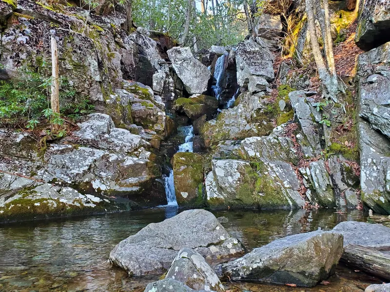 Water cascading between large mossy boulders into a rock-lined pool at White Rock Falls