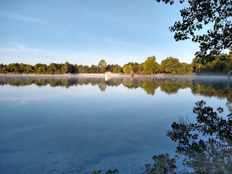 White Star Quarry with trees reflected in the water and the beach on the far shore