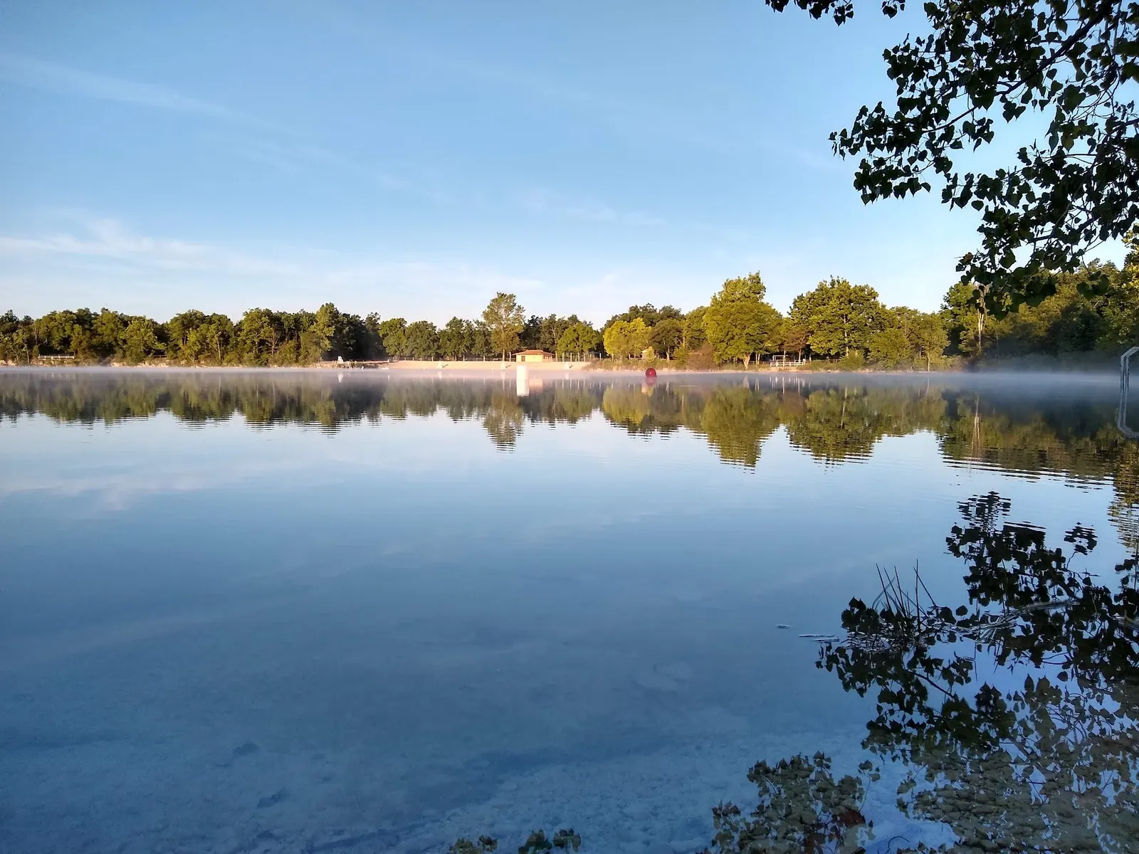 White Star Quarry with trees reflected in the water and the beach on the far shore