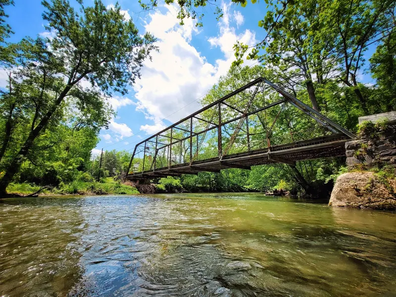 Metal truss bridge crossing Yellow Breeches Creek among trees, shown as creek-level scenery